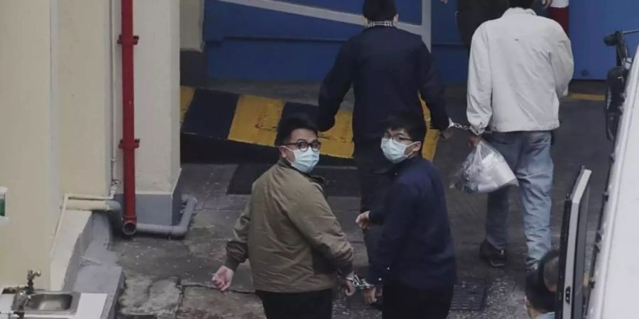 Die Aktivisten Ivan Lam (l.) und Joshua Wong wurden auf einem Gefängnishof in Hongkong von Justizvollzugsbeamten aneinandergekettet. Der prominente Hongkonger Pro-Demokratie-Aktivist Wong und zwei weitere Aktivisten, Lam und Chow, wurden in Gewahrsam genommen. Foto: Uncredited/Apple Daily/dpa