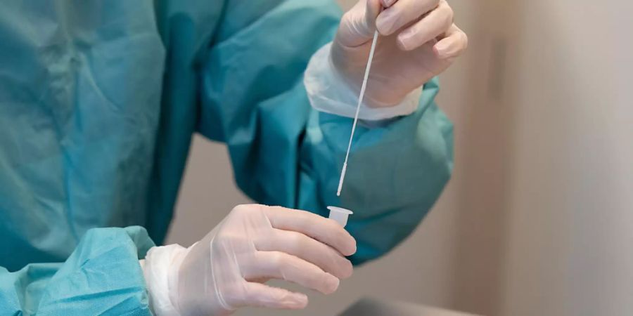 Eine Apothekerin rührt einen Covid-19-Abstrichstab in Flüssigkeit für einen Covid-19 Antigen-Schnelltest.