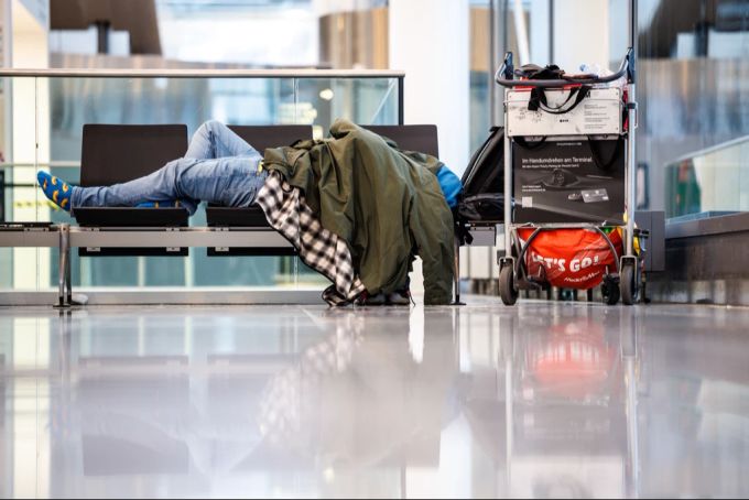 Reisende müssen sich auf massive Einschränkungen am Münchner Flughafen einstellen. (Archvbild) Münchner Flughafen schlafender Reisender