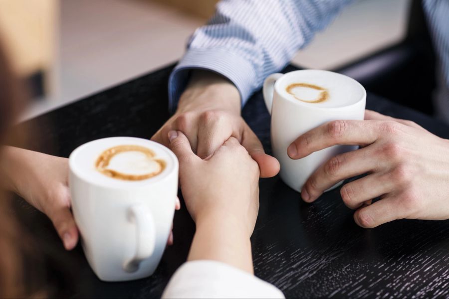 Hände eines Pärchens beim Kaffeetrinken