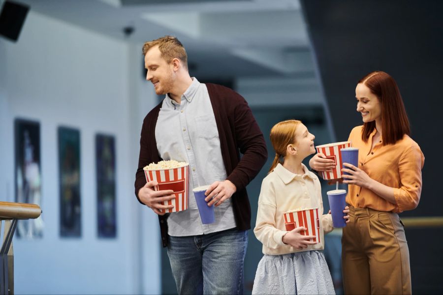 Familie auf dem Weg ins Kino mit Popcorn und Cola.