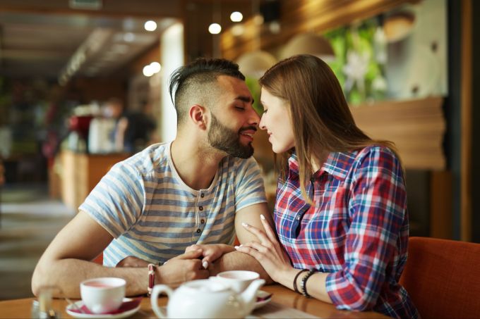 Berührungen schaffen Intimität und sind eine der fünf Liebessprachen. Paar zärtlich im Café