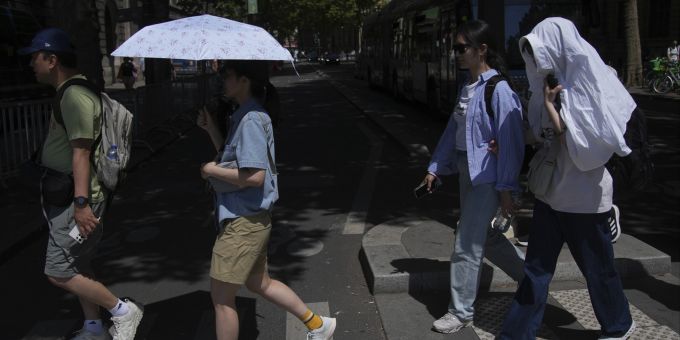 Touristen laufen am 1. Juli mit Sonnenschirmen durch Paris. Hitze Frankreich