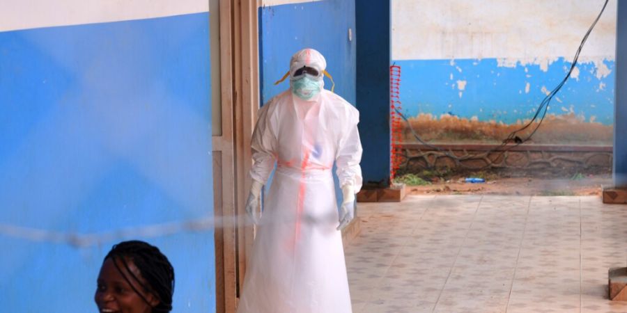 ARCHIV - Ein Mitarbeiter des Gesundheitswesens steht vor einem Ebola-Behandlungszentrum im Kongo. Foto: Dirole Lotsima Dieudonne/AP/dpa/Archivbild