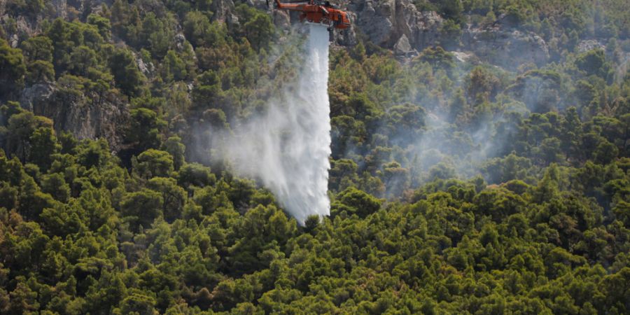 ARCHIV - Ein Löschhubschrauber wirft in Griechenland Wasser über einem Wald ab. Foto: Socrates Baltagiannis/dpa/Archivbild