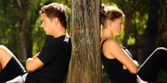 Mann und Frau mit dem Rücken an den Baum gelehnt. Streit.