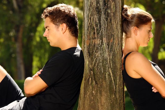 Mann und Frau mit dem Rücken an den Baum gelehnt. Streit.