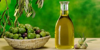 Flasche Olivenöl, daneben Oliven