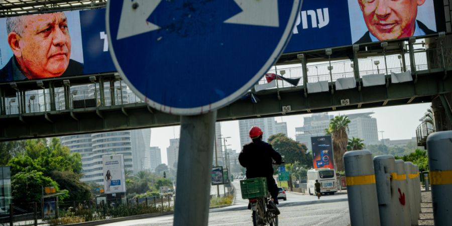 ARCHIV - Ein Radfahrer fährt unter einer Fußgängerbrücke hindurch, an der elektronische Wahlplakate zu sehen sind, auf denen der ehemalige Stabschef der israelischen Streitkräfte, ...