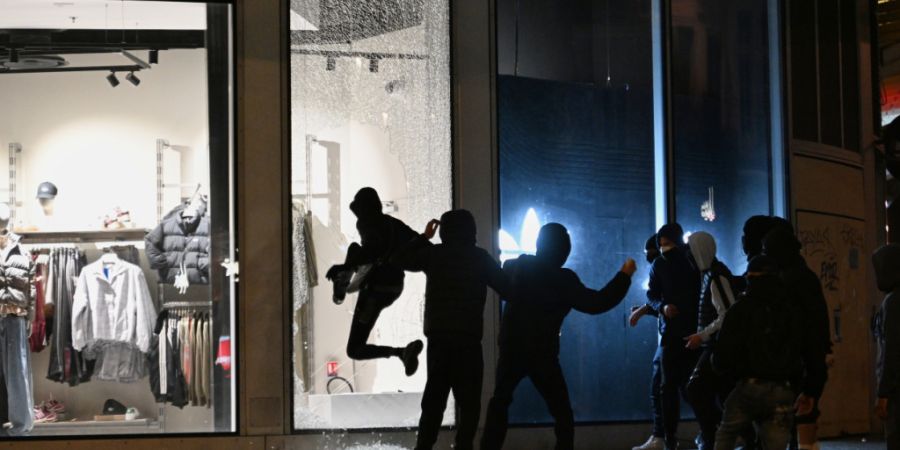 dpatopbilder - Jugendliche zerschlagen bei Zusammenstößen zwischen Demonstranten und der Polizei in Paris eine Schaufensterscheibe. Foto: Emma Da Silva/AP/dpa