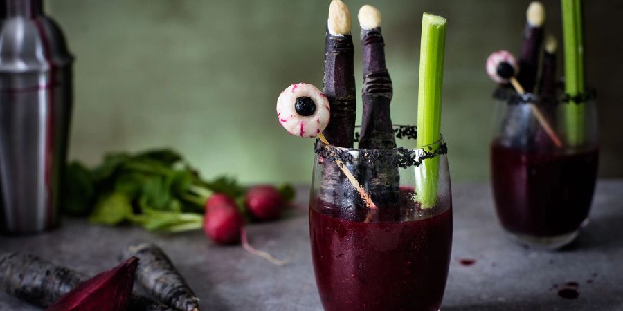 Zu Fingern geschnitzte lila Möhren und Glubschaugen aus Radieschen und Blaubeeren geben der Bloody Mary einen schaurig-schönen Touch.
