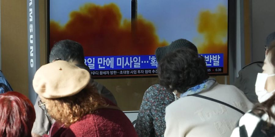 Menschen sitzen nahe eines Monitors auf dem eine Nachrichtensendung mit einem Archivbild über den neusten Raketentest Nordkoreas berichtet. Foto: Ahn Young-Joon/AP/dpa