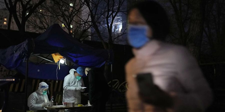 ARCHIV - Eine Anwohnerin geht in Peking an einer Station zur Entnahme von Abstrichproben für Corona-Tests vorbei. Foto: Ng Han Guan/AP/dpa