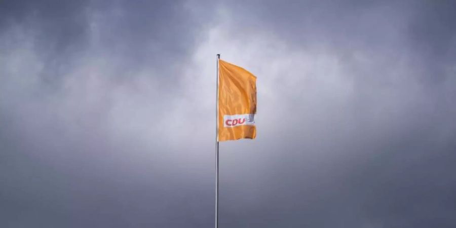 Die CDU-Fahne weht auf dem Konrad-Adenauer-Haus in Berlin - vor dunklen Wolken. Foto: Michael Kappeler/dpa