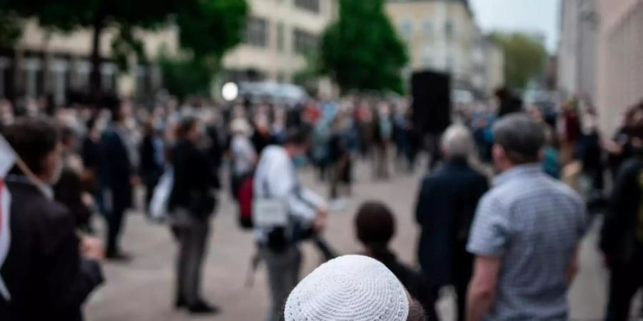 Menschen stehen bei einer Solidaritätskundgebung in Gelsenkirchen auf dem Platz vor der Synagoge. Dabei trägt ein Mann eine Kippa. Foto: Fabian Strauch/dpa