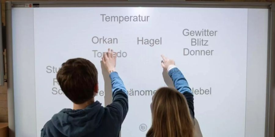 Ein Schüler und eine Schülerin arbeiten an einem Smartboard. Foto: Daniel Reinhardt/dpa