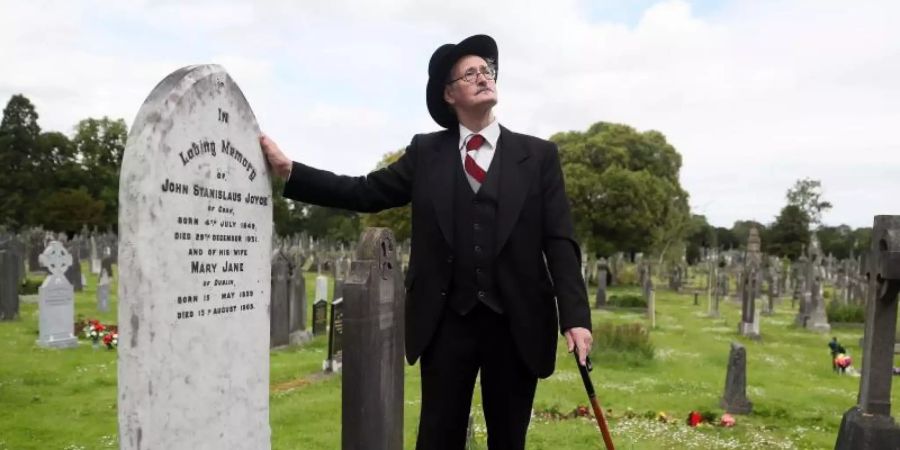 Ein James-Joyce-Darsteller am Grab des Schriftstellers James Joyce und seiner Frau in Dublin (2019). Foto: Brian Lawless/PA Archive/dpa