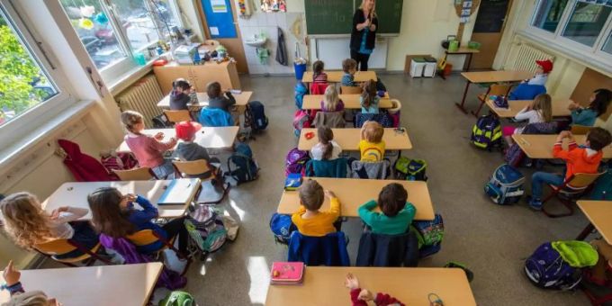 Schüler einer ersten Grundschulklasse sitzen im Unterricht auf ihren Plätzen. Schüler