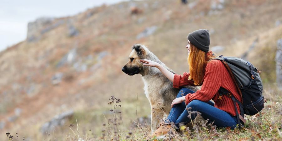 Eine Wanderin mit ihrem Hund in den Bergen.
