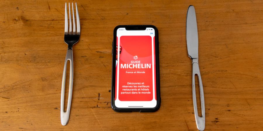 Roter Michelin-Führer über Smartphone-Anwendung, die Restaurants bewertet.