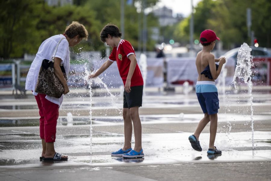 Menschen suchen in Genf am Place des Nations wegen der hohen Temperaturen Abkühlung.