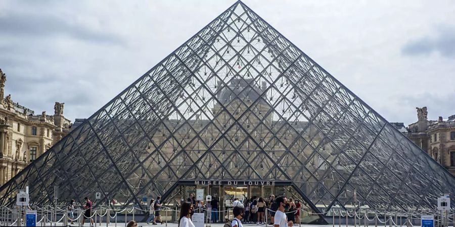 ARCHIV - Eine Familie mit Schutzmasken geht am Louvre vorbei. (zu dpa «Corona-Krise: Frankreich kommt seinen grossen Museen zu Hilfe») Foto: Kamil Zihnioglu/AP/dpa