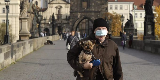 Ein Mann in Schutzmaske gegen das Coronavirus trägt seinen Hund in Prag, Tschechien. Coronavirus Czech Republic