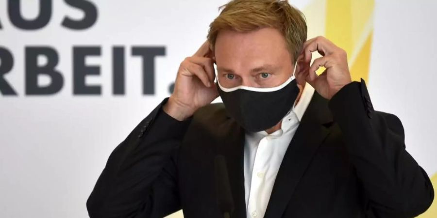 Christian Lindner, Bundesvorsitzender der FDP, legt einen Mund-Nasen-Schutz auf einer Pressekonferenz an. Die Bundestagsfraktion der FDP traf sich zu ihrer Klausurtagung im Reichstagsgebäude. Foto: Johannes Neudecker/dpa