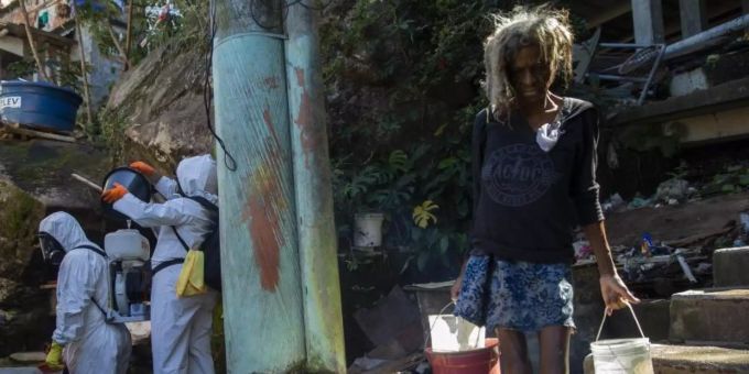 Eine Bewohnerin in einer Favela in Rio de Janeiro holt Wasser, während Freiwillige versuchen das Viertel zu desinfizieren. Foto: Fernando Souza/dpa brasilien