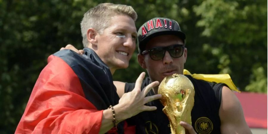 Bastian Schweinsteiger und Lukas Podolski posieren mit dem WM-Pokal nach dem Gewinn der Weltmeisterschaft 2014.