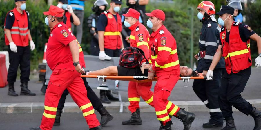Ein verletzter Demonstrant wird von Rettungskräften mit einer Trage weggebracht. Bei gewaltsamen Auseinandersetzungen von Polizei und Demonstranten am Rande von massiven Protesten gegen Rumäniens Regierung sind in Bukarest mehrere hundert Menschen verletzt worden.