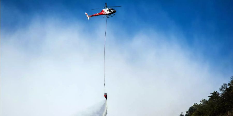 Ein Helikopter löscht im Wallis ein Feuer.