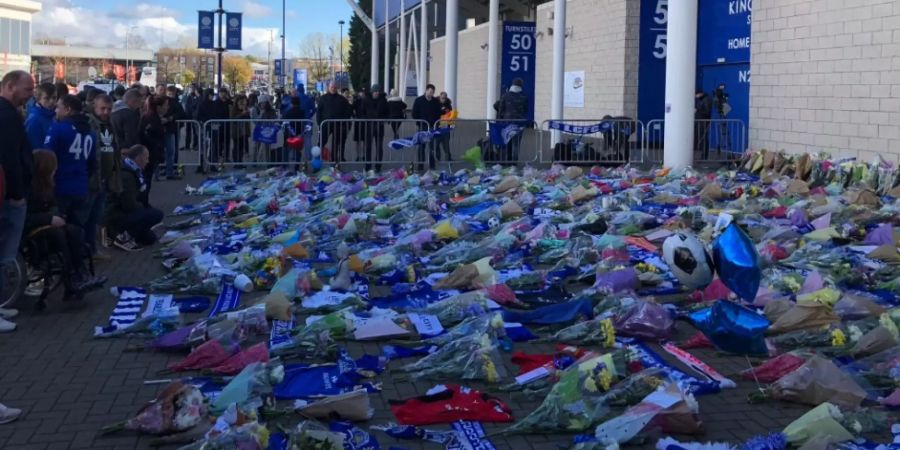 Die Menschen legen Blumen vor das Fussballstadion.