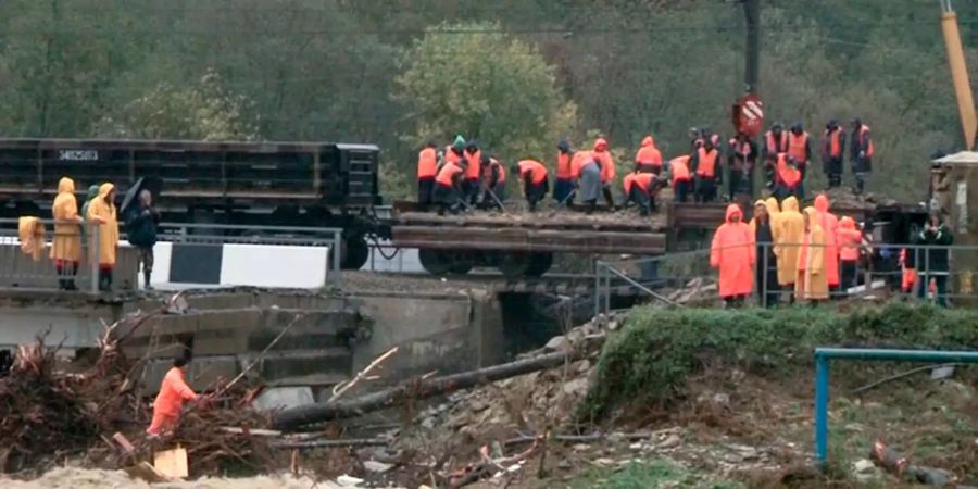 Dieses vom russischen Notfallministerium zur Verfügung gestellte Videostandbild zeigt Mitarbeiter des Ministeriums bei einer nach heftigen Regenfällen teilweise eingestürzten Eisenbahnbrücke.