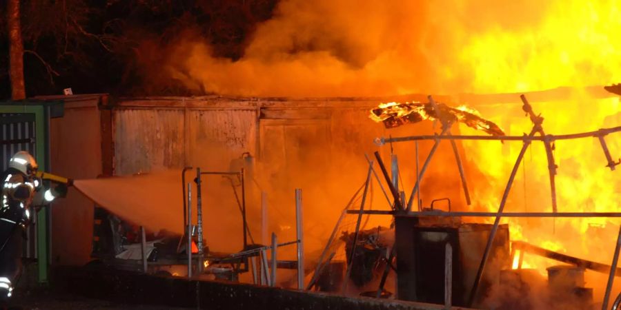 Ein Feuerwehrmann versucht den Brand eines Geräteunterstands in Gerlafingen SO zu löschen.