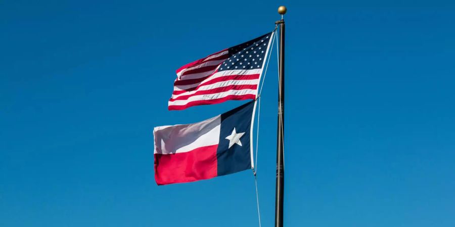 Im Wind wehen die Fahnen der USA und von Texas.