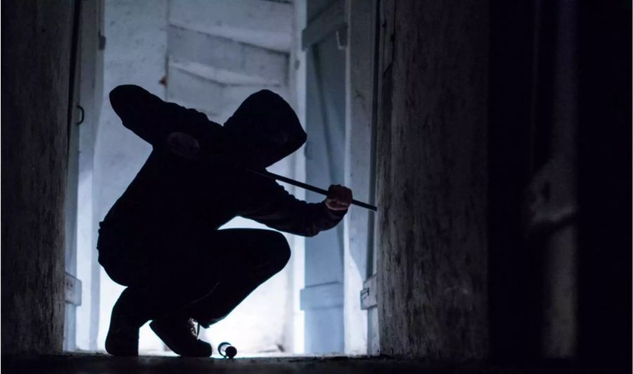 Dunkel gekleidete Person bricht in Gebäude ein - Keystone