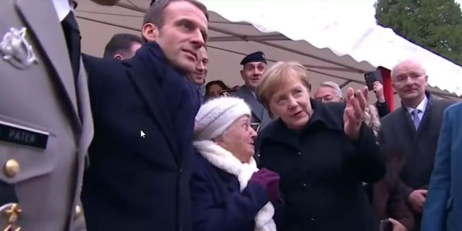 Angela Merkel spricht zusammen mit Emmanuel Macron mit einer 101-Jährigen.