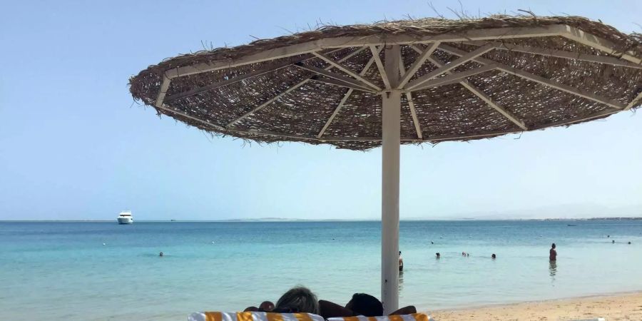 Eine Frau und ein Mann entspannen in Liegestühlen unter einem Sonnenschirm an einem öffentlichen Strand. Nach zwei mysteriösen Todesfällen in einem Hotel im ägyptischen Badeort Hurghada hat der britische Reiseveranstalter Thomas Cook alle seine Gäste von dort ausquartiert.