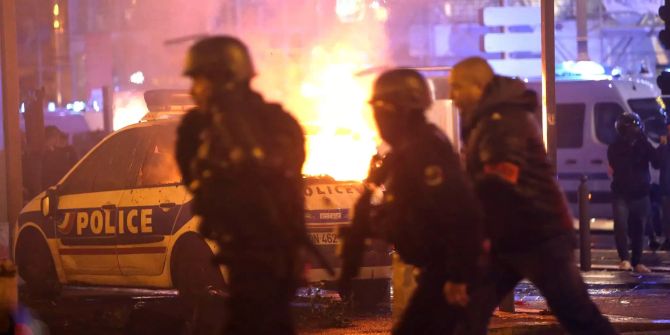 Die Polizei nimmt Position in der Nähe eines brennenden Polizeiwagens ein, bei einem Protest der sich gegen den Sanierungsstau in der Stadt richtet.