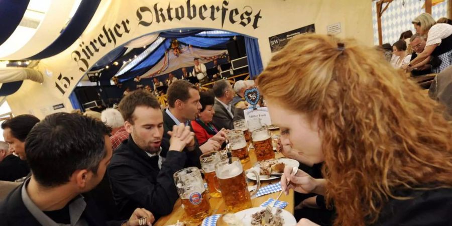 Gäste geniessen eine Mass Bier und Brathähnchen, nachdem "O'zapft is ", bei der Eröffnung des 15. Zürcher Oktoberfestes auf dem Bauschänzli.