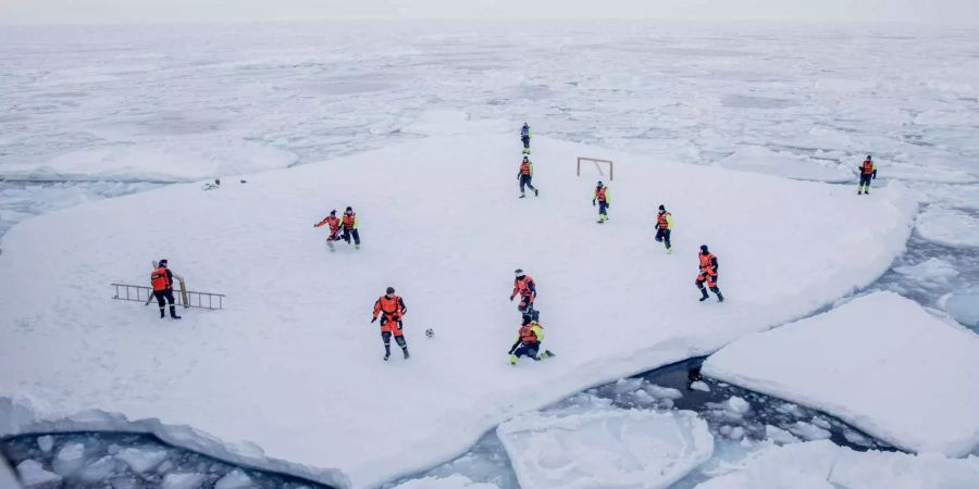 Forscher und Soldaten beim Fussballspielen auf einer Eisscholle vor Grönland.