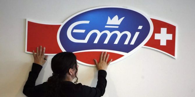 eine Frau befestigt das Logo von Emmi.