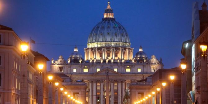 Der beleuchtete Petersdom im Vatikan bei Nacht.