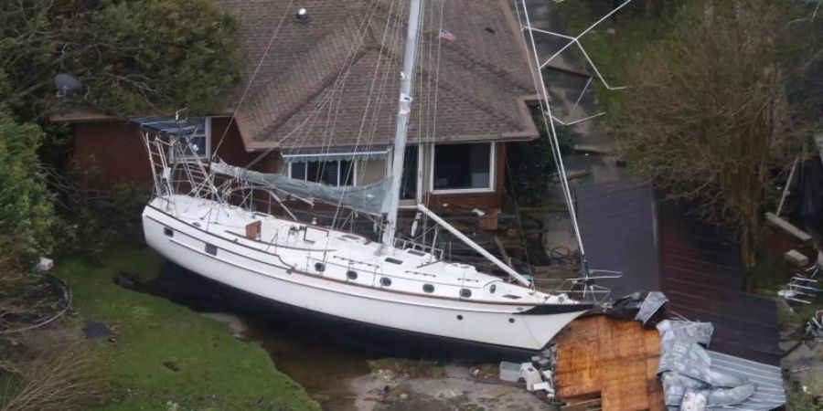 Ein Segelboot liegt nach dem Hurrikan "Florence" in den USA vor einem Wohnhaus. Foto: Steve Helber/AP/dpa