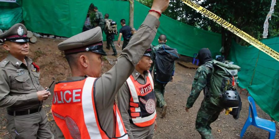 Thailändische Polizisten halten für die Rettungstaucher den Weg frei.