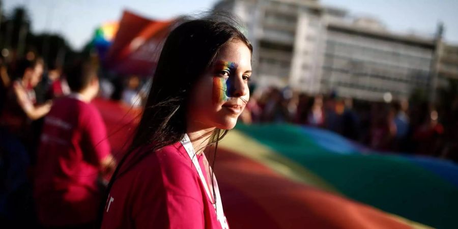 Eine Frau hält die Regenbogenfahne vor dem griechischen Parlament.