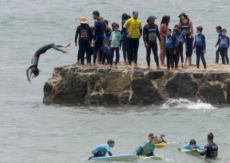 Da kommt eine Abkühlung im Meer gerade recht: Menschen beim Baden und Surfen in Spanien.