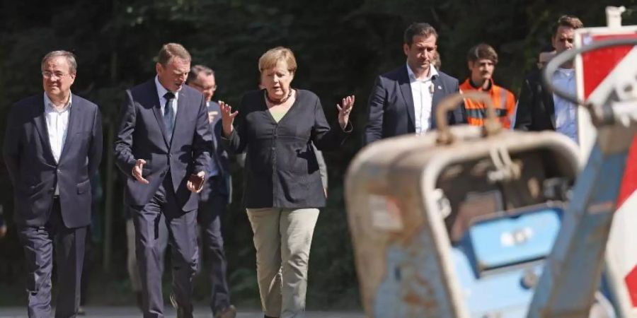 Angela Merkel und Armin Laschet begutachten eine neugebaute Brücke in Hagen. Die Bundeskanzlerin hat erneut die Flutgebiete in Nordrhein-Westfalen besucht. Foto: Oliver Berg/dpa Pool/dpa