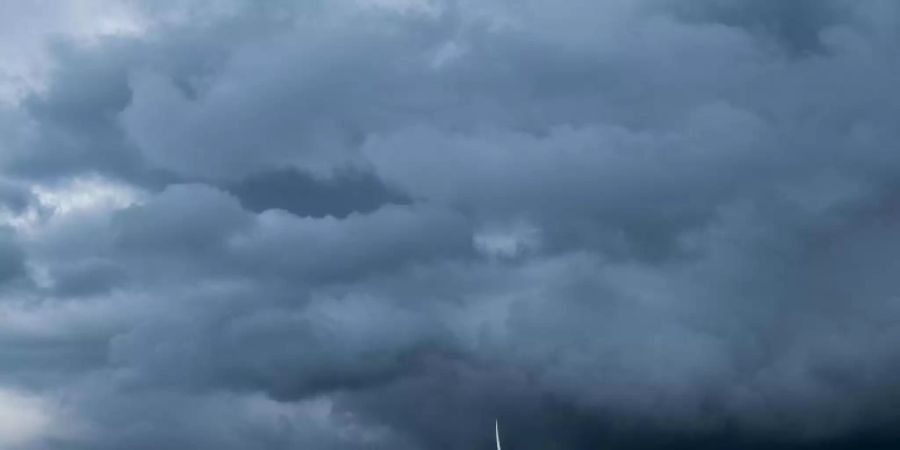 Eine Gewitterzelle mit dunklen Wolken zieht über Windräder in der Region Hannover hinweg. Foto: Julian Stratenschulte/dpa